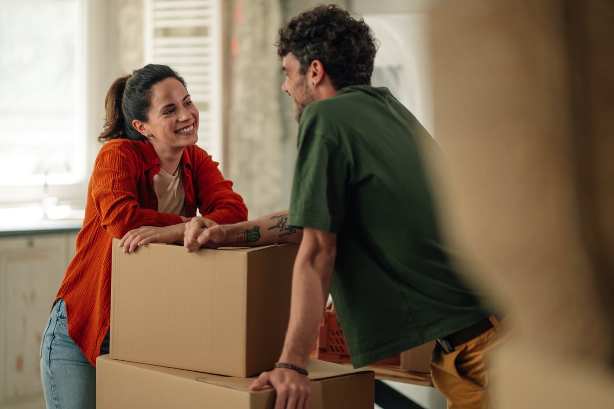 A couple taking a break from unpacking and smiling in their new home